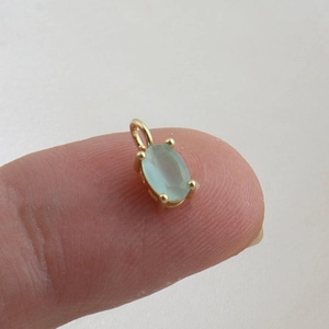 Macro shot of an oval light green gemstone pendant in a four-prong gold setting