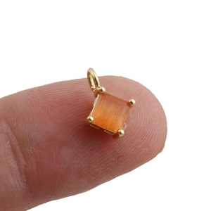Minimalist 18k gold plated square orange zircon pendant shown on a fingertip for size