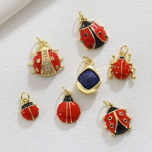 Detail of red enamel ladybug charms and blue stone pendant with 18k gold plating