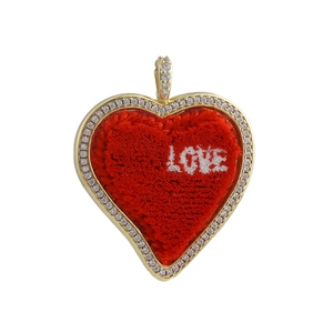 Close-up of heart charm with red velvet inlay, gold plated edge and LOVE embroidery