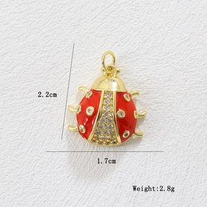Macro detail of 18k gold plated ladybug charm with red enamel and zircon stones