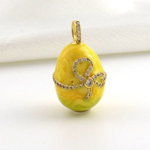Detailed close-up of a vintage yellow enamel egg pendant with 18k gold plating and crystals