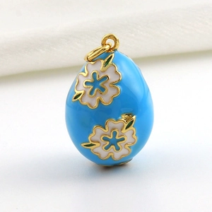 Detail of egg-shaped pendant with light blue enamel and white floral gold-plated patterns