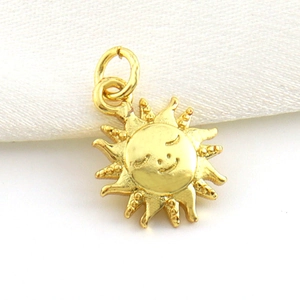 Macro shot of a 18k gold plated sun pendant with a smiling face and radiating textures