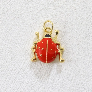 Macro detail of a 18k gold-plated ladybug pendant with red enamel and golden dots