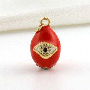 Macro detail of red enamel teardrop charm with evil eye design and zircon inlay