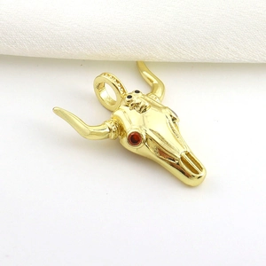Detailed view of a gold bull skull pendant with red cubic zirconia eyes and black accents