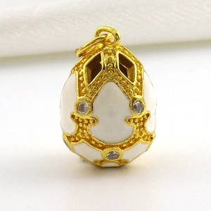 Close-up of gold-plated Faberge-style egg pendant with white enamel and sparkling crystals