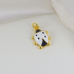Detail of 18k gold plated ladybug pendant with red enamel on white silk background