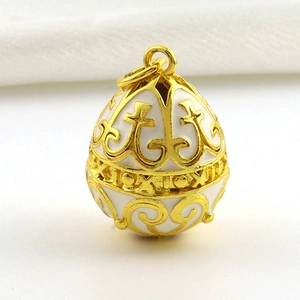 Macro view of white enamel 18k gold plated Fabergé style egg pendant with filigree details
