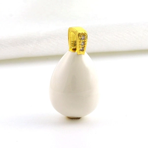 Macro shot of egg-shaped white enamel pendant with gold clasp and inset cubic zirconia