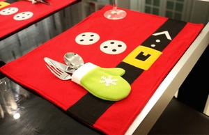Close-up of a festive red Santa belt placemat and green snowflake cutlery glove set
