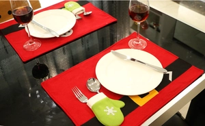 Close-up of Santa belt placemat and green snowflake mitten cutlery holder on dining table