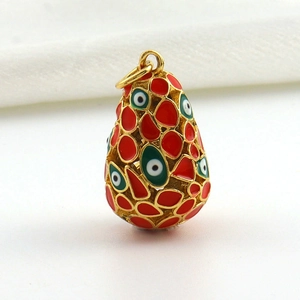 Macro detail of 18k gold plated Easter egg pendant with red enamel and evil eye motif