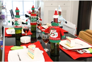 Close-up of festive knit Christmas wine bottle covers with holiday sweaters and hats