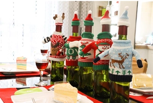 Detail of festive knitted Christmas wine bottle covers with reindeer and JOY patterns