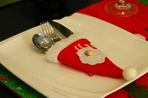 Dettaglio portaposate di Babbo Natale con coltello e forchetta su un piatto bianco