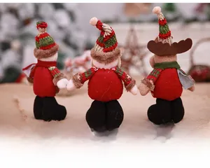 Rear view of three Christmas plush dolls with striped hats and red festive outfits