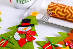 Detail of felt Christmas tree cutlery holder featuring a cute snowman with metal flatware