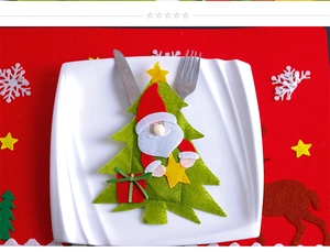 Detail of felt Christmas tree cutlery holder with Santa Claus on a white dinner plate