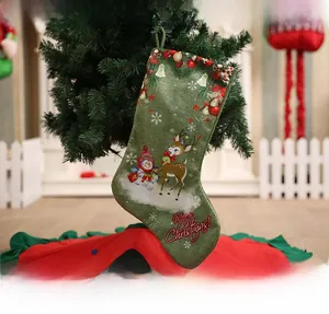 Detail of green Christmas stocking with elk and snowman prints hanging on a tree