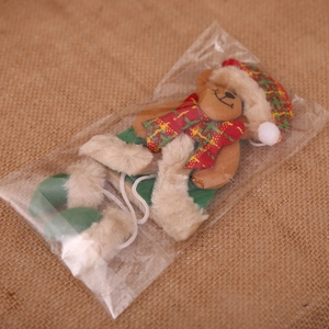 Orsetto di Natale in peluche con sciarpa e cappello su sfondo in tela grezza
