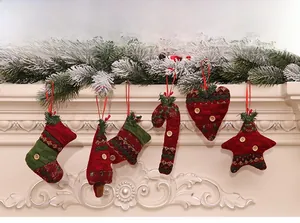 Close-up of red and green plaid fabric Christmas ornaments hanging on a white fireplace