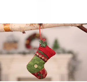 Detail of a red and green knitted Christmas stocking with a wooden button and hanging rope