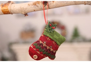 Detail of red and green knit Christmas stocking ornament with pine needles and wood button