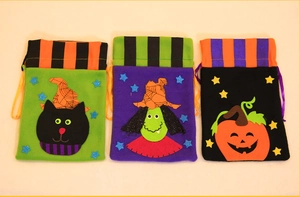 Three Halloween drawstring gift bags with black cat, witch, and pumpkin patterns