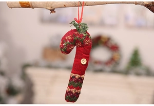 Close-up of knit candy cane ornament with a wooden button on a rustic tree branch