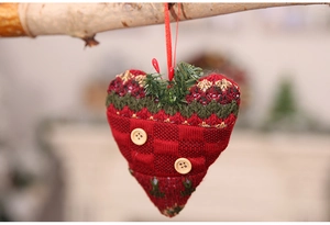 Macro detail of red knitted heart ornament with wooden buttons and pine needle decor