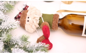 Detail of Santa Claus wine bottle cover with plaid hat and soft fabric on festive table