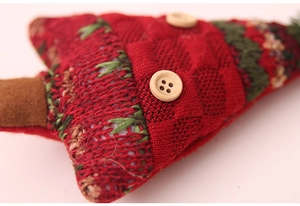Close-up of red knitted Christmas tree ornament with green stitching and wood buttons