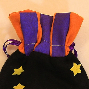 Halloween pumpkin drawstring treat bag with purple satin ribbon and yellow star accents