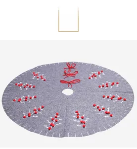 Detail of grey felt Christmas tree skirt featuring white embroidery and red pom-poms