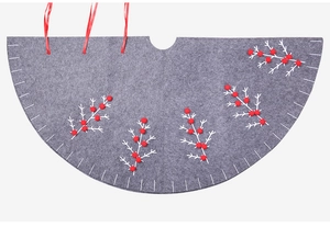 Close-up of grey felt Christmas tree skirt with white branches and red pom-poms