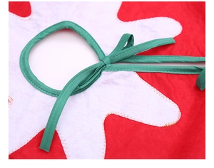 Close-up of red and white felt Christmas tree skirt with green ribbon tie closure