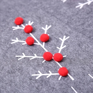 Gray felt Christmas tree skirt with white branch prints and red pom-pom decorations