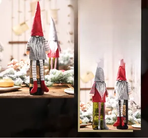 Christmas gnome wine bottle covers in red and grey with striped legs on wooden table