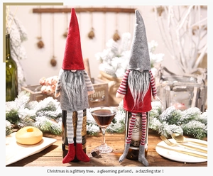 Close-up of festive Christmas gnome wine bottle cover with long striped legs on wooden table