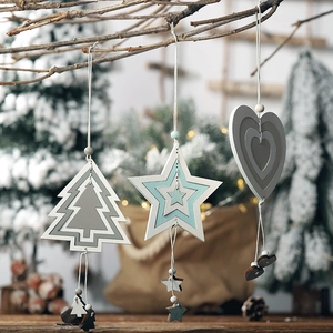 Three-piece set of wooden Christmas ornaments hanging on a tree with warm festive lighting
