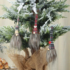 Close-up of three festive Christmas gnomes with plaid hats hanging on a snowy tree branch
