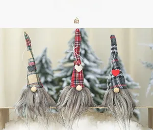 Close-up of three Christmas gnomes with plaid hats and heart details on white snow