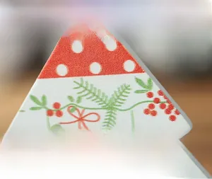 Detailed macro view of a wooden Christmas tree ornament with festive red and green prints