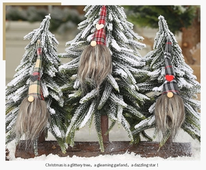 Detailed view of three Christmas gnomes with plaid hats hanging on a snowy tree
