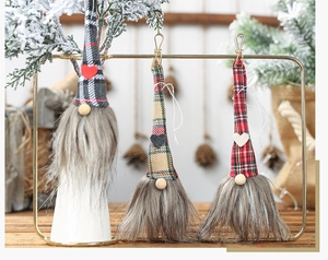 Three Christmas gnomes with plaid hats and metal clips hanging on a gold display rack