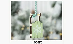 Detailed front view of a green wooden ski sled ornament with white snowflake patterns