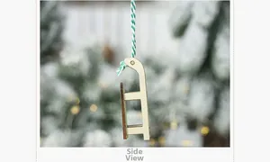 Detail of wooden Christmas sled ornament with festive cotton rope on snow-covered tree