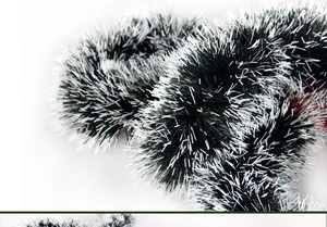 Close-up of dark green Christmas tinsel with white tips showing fluffy texture details